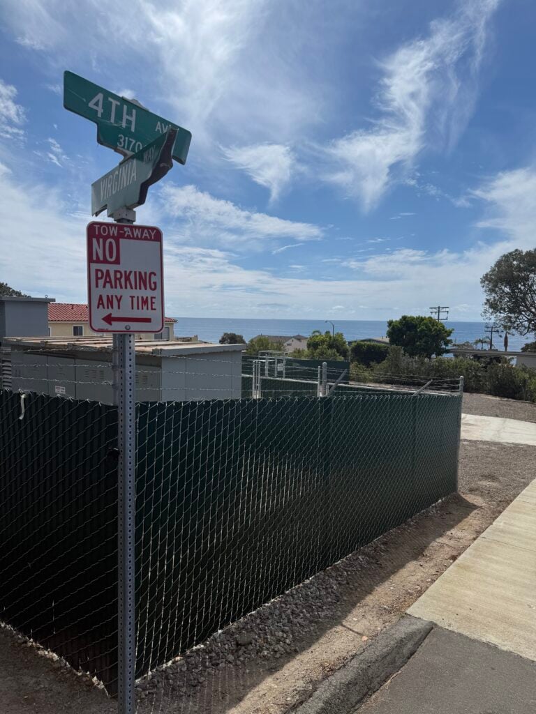 Current view of the South Laguna Water District lot at Virginia Way and 4th Ave, showing bare dirt, chain-link fencing, and lack of promised site restoration or pocket park landscaping as of April 2026.