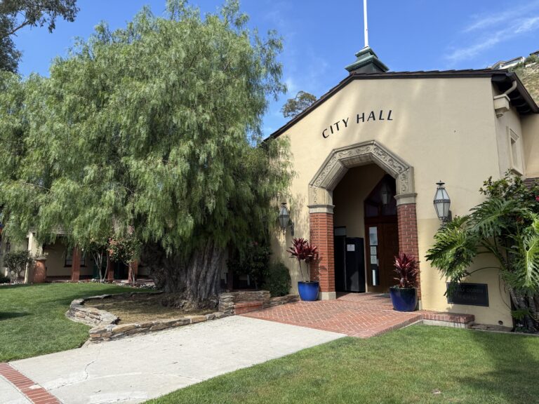 Exterior view of Laguna Beach City Hall and a California pepper tree, promoting civic engagement and committee applications.
