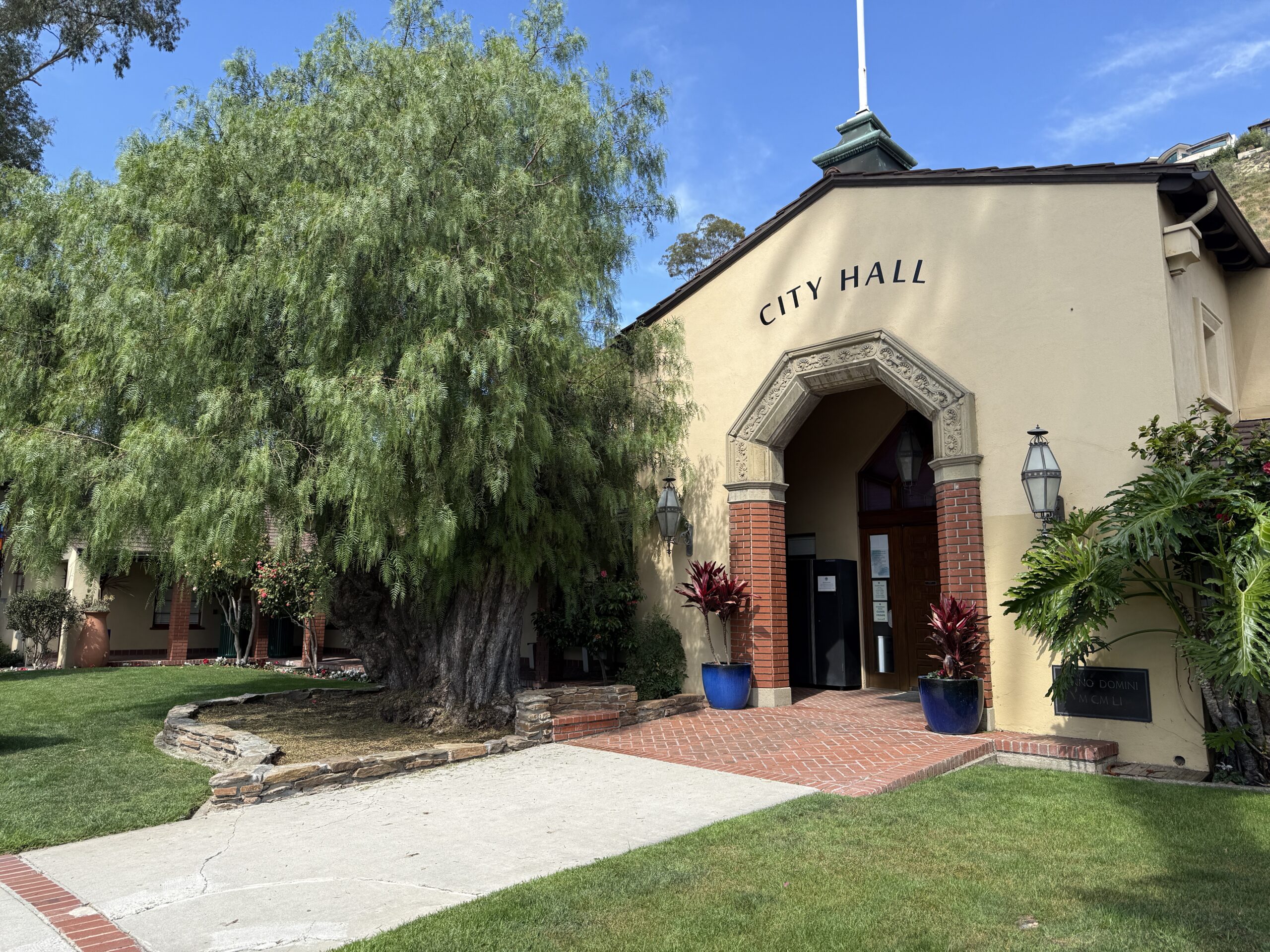 Exterior view of Laguna Beach City Hall and a California pepper tree, promoting civic engagement and committee applications.