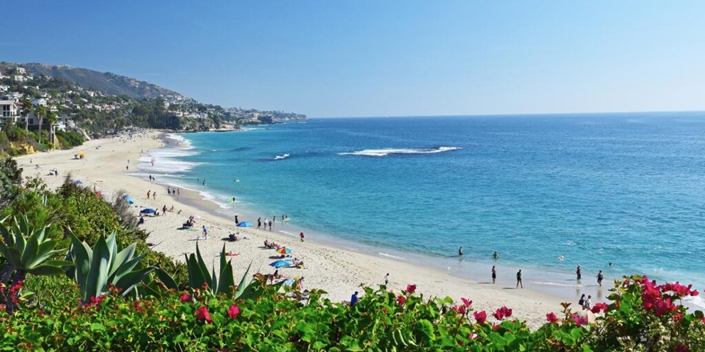 Panoramic view of the Laguna Beach coastline, beachgoers, and coastal homes.
